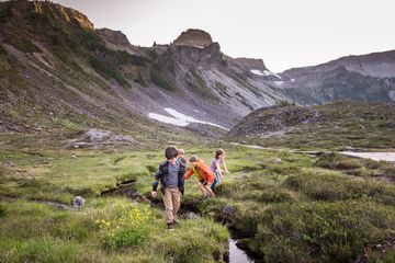 Children playing in a field surrounded by mountains 