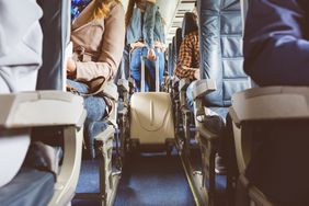 Passengers with suitcase in aisle looking for seat during flight boarding