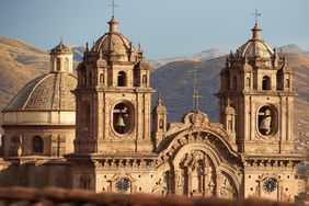 Twin towers and dome of the historic Iglesia de la Compania seen across the red rooftops of Cusco in Peru. The church dates back to 1571 and sits on top of an old Inca Palace.