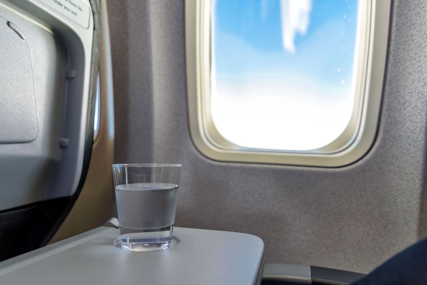 glass of water in a glass on an airplane tray table