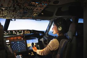 Rear view of a female pilot sitting the cockpit of a flight. Woman pilot flying an airplane.