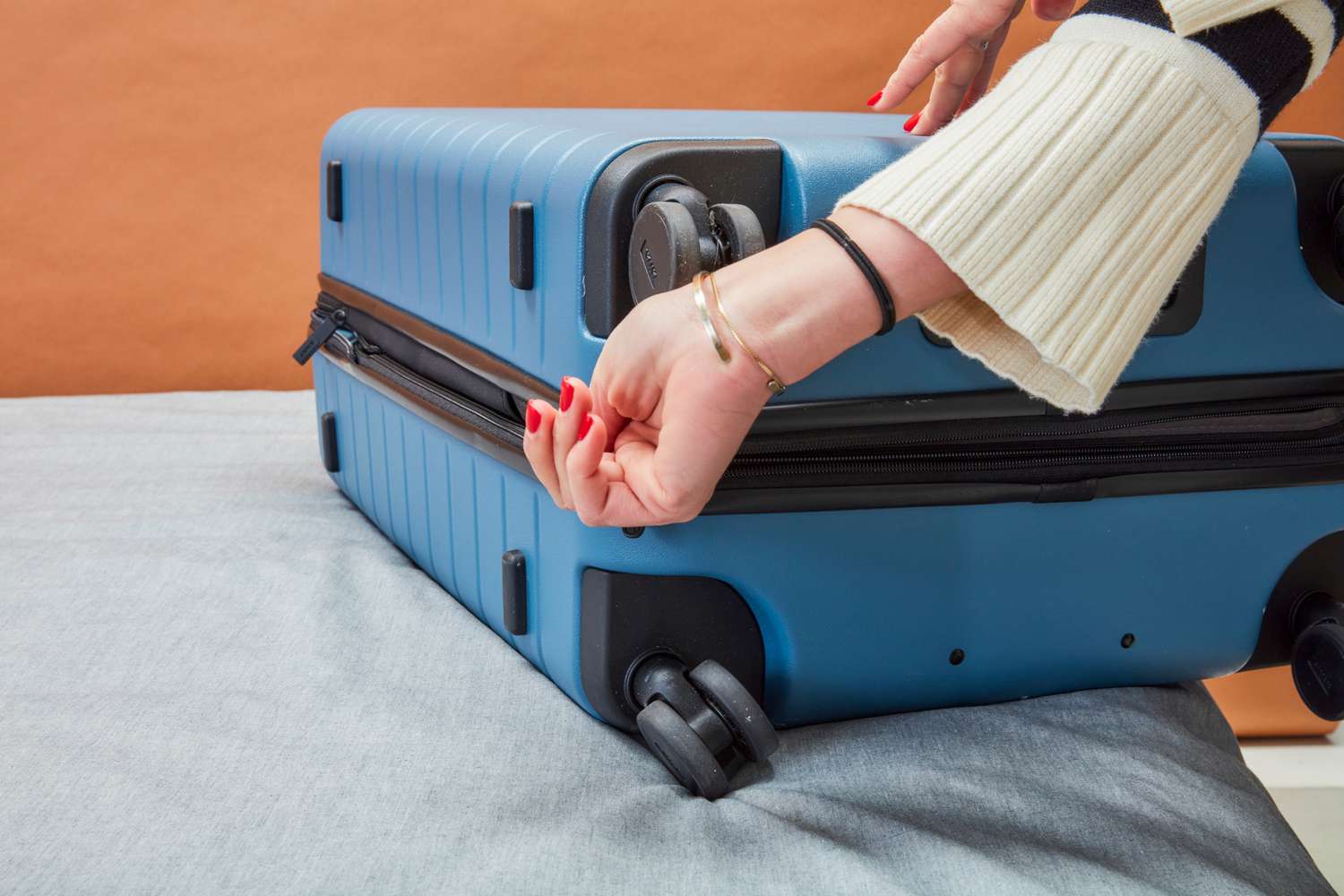 A person zipping the The Away medium carry-on