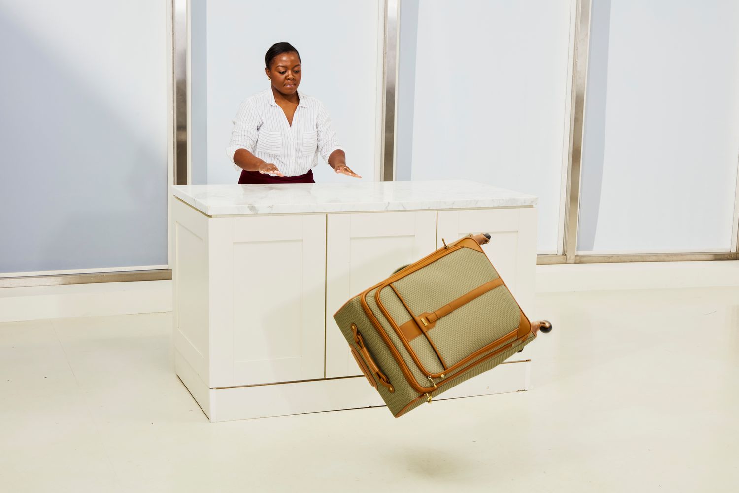 A person pushing the Hartmann Luxe II Medium Journey Luggage off of a counter