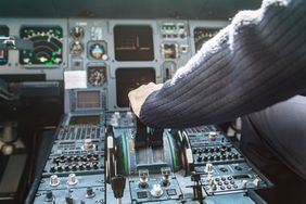 A pilot's hand on the controls of a plane.