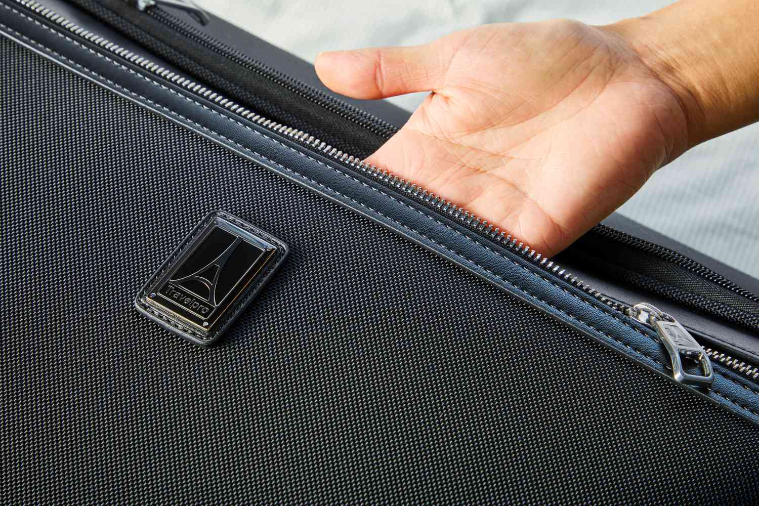 Close up of a hand partially inside of the Travelpro Platinum Elite Check-In Rolling Garment Bag