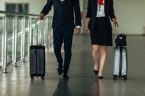 A man and a woman are pulling their suitcases toward the exit