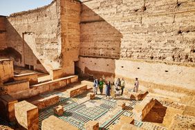 Extreme wide shot of group of tourists exploring the ruins of El Badi Palace with tour guide while on vacation in Marrakech