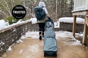 A person pulling the Thule RoundTrip Ski Roller Bag on a snowy patio