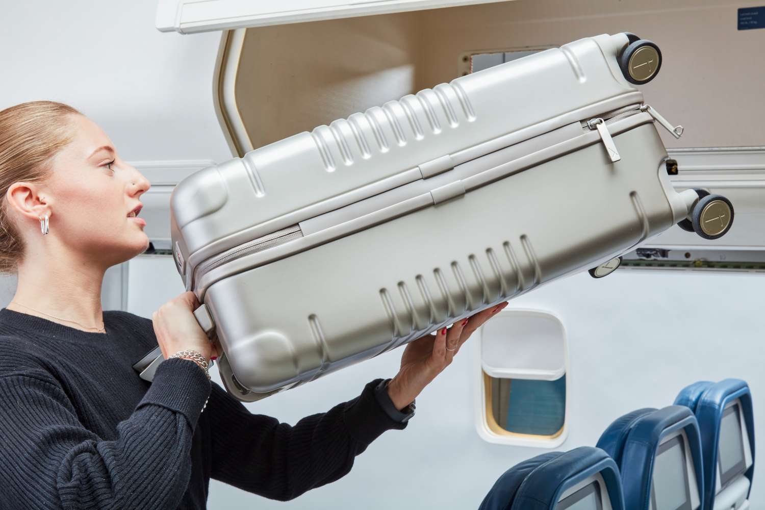 Person putting Arlo Skype Zipper Carry On into Airplane Container