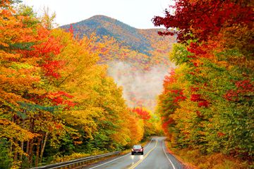 An electric car driving down the Kancamagus Highway in Northern New Hampshire