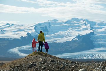 Family stands on mound looking at the vast snowy landscape of glaciers in Iceland