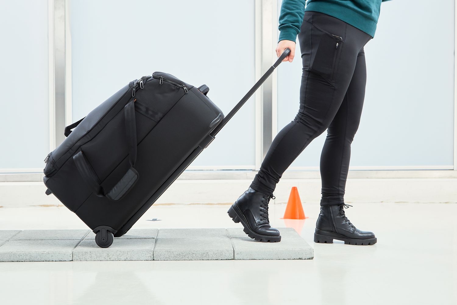 A woman wheels a Briggs & Riley ZDX 27 Medium Upright Duffle over tile in a testing lab.