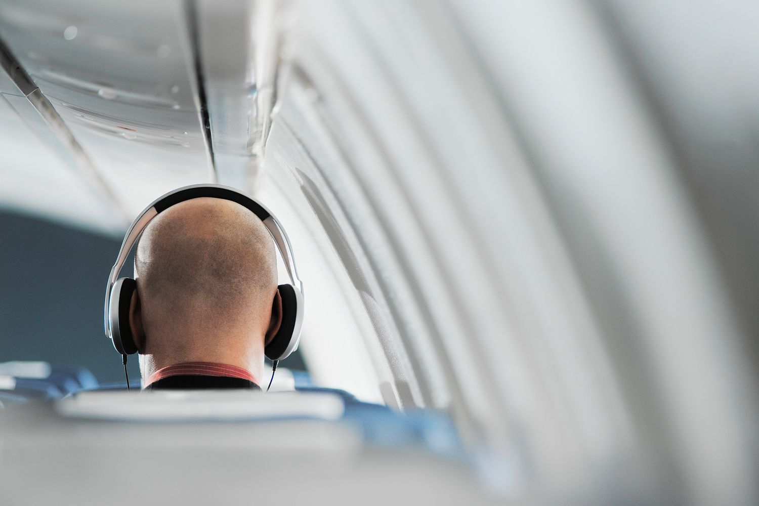 Businessman sitting on airplane seat, wearing headphones