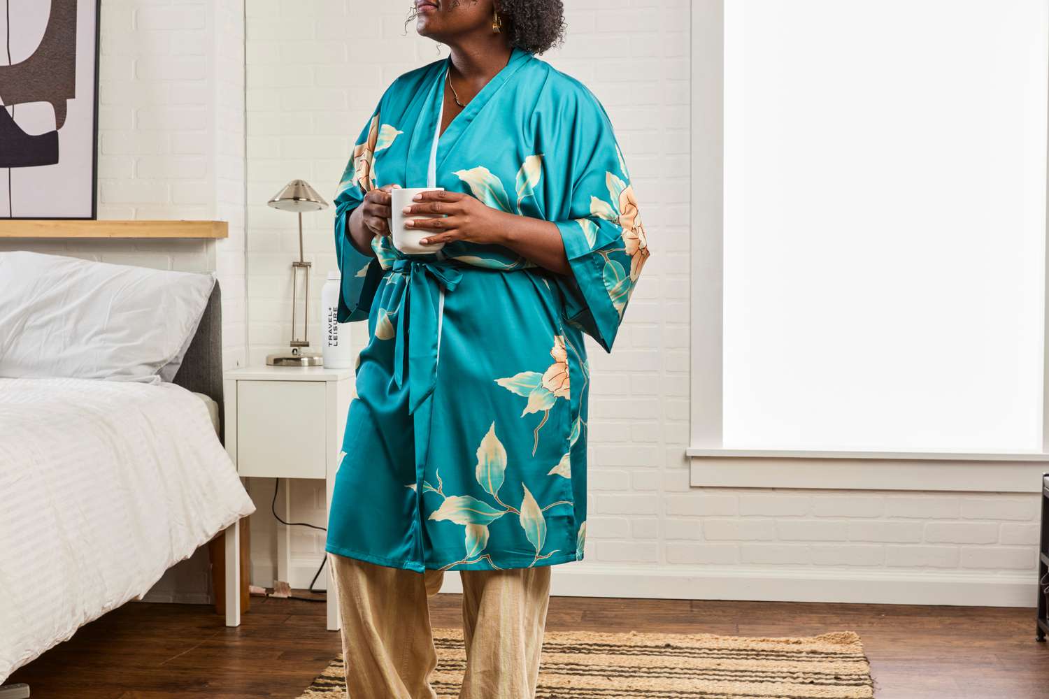 A person wears the KIM+ONO Short Kimono Robe in a bedroom setting