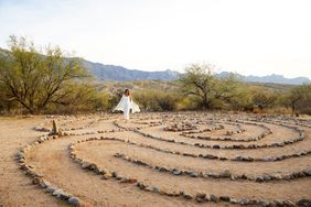 A person in white walks the rock bordered labyrinth for mindful reflection