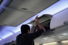 Passenger looking for bag in airplane overhead bin 