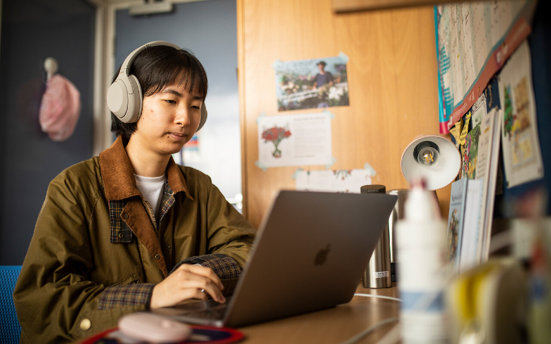 A student works at a laptop in a UCL student accommodation room.