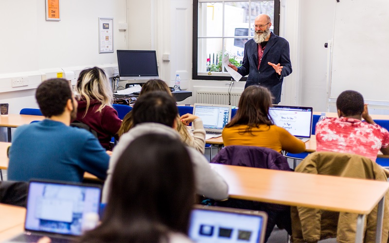 A UCL CLIE tutor addresses a class.