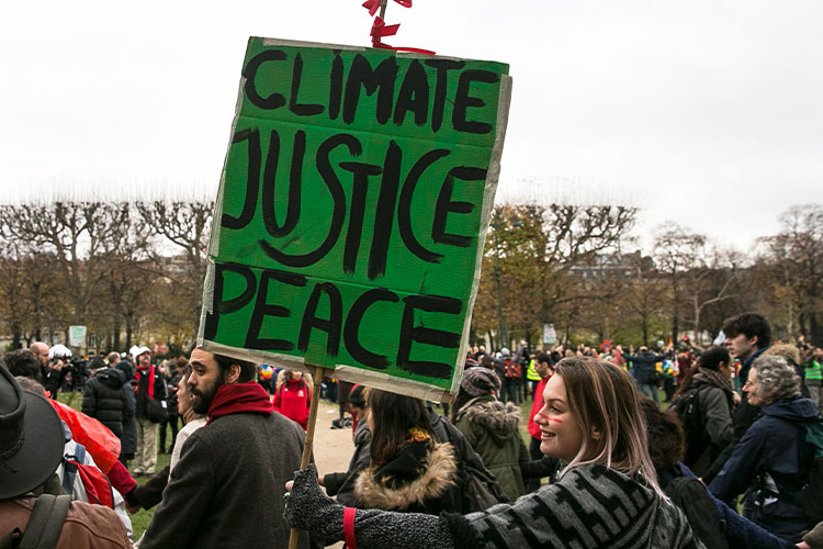 protesters carrying sign Climate, Justice, Peace