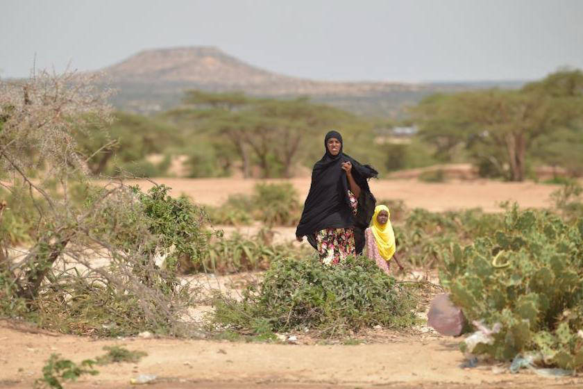 woman and girl walking through drought-stricken land