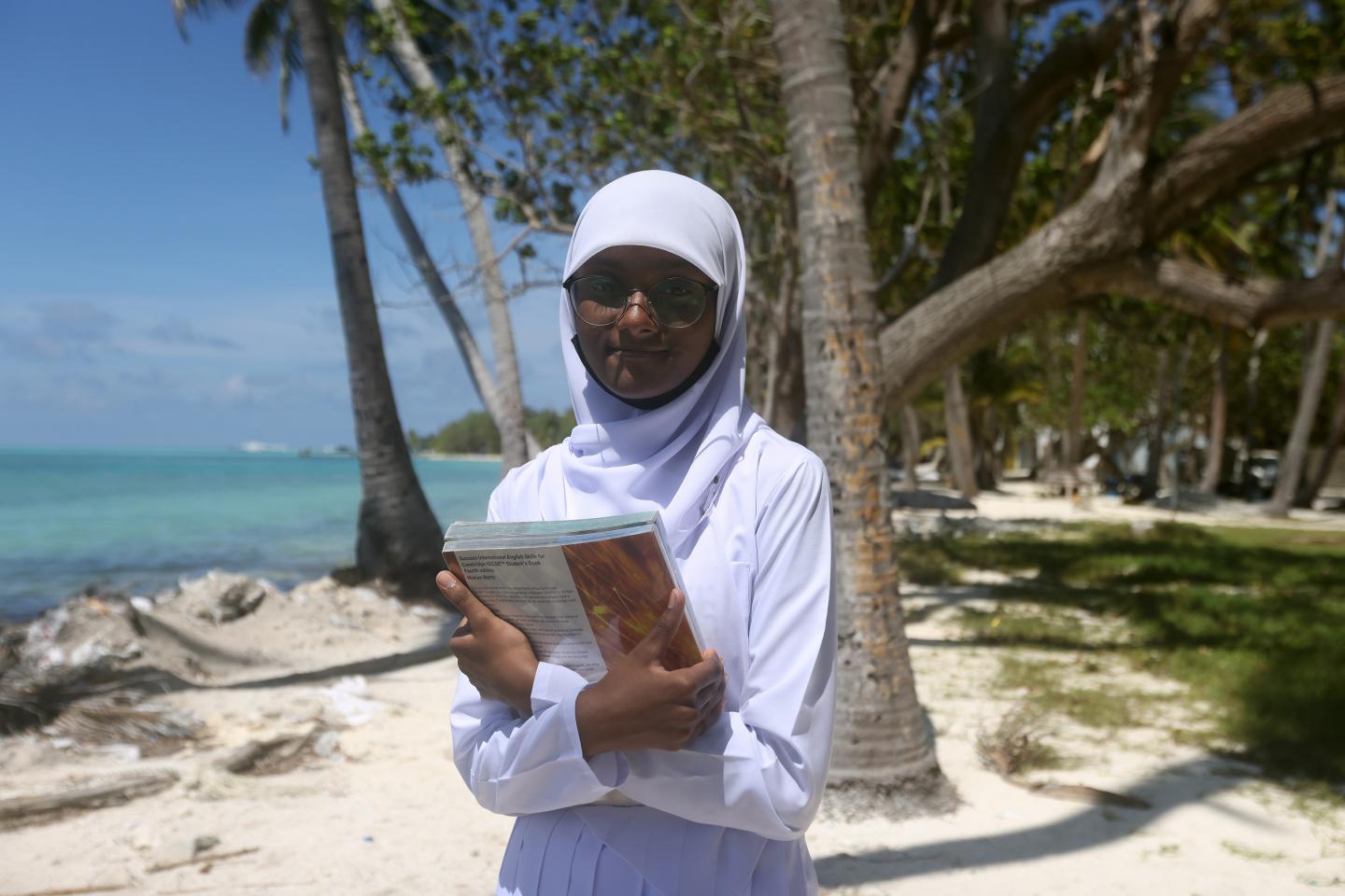 girl on beach holding school book