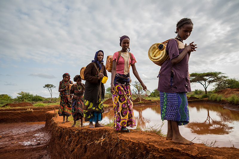 girls and women walking along flooded land