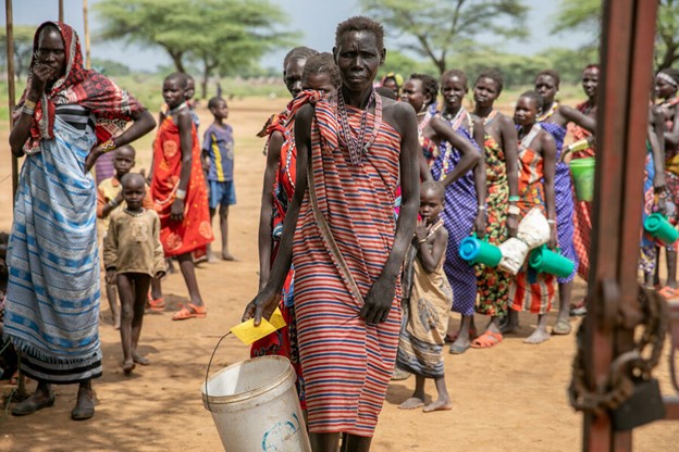 A woman standing in line with a bucket