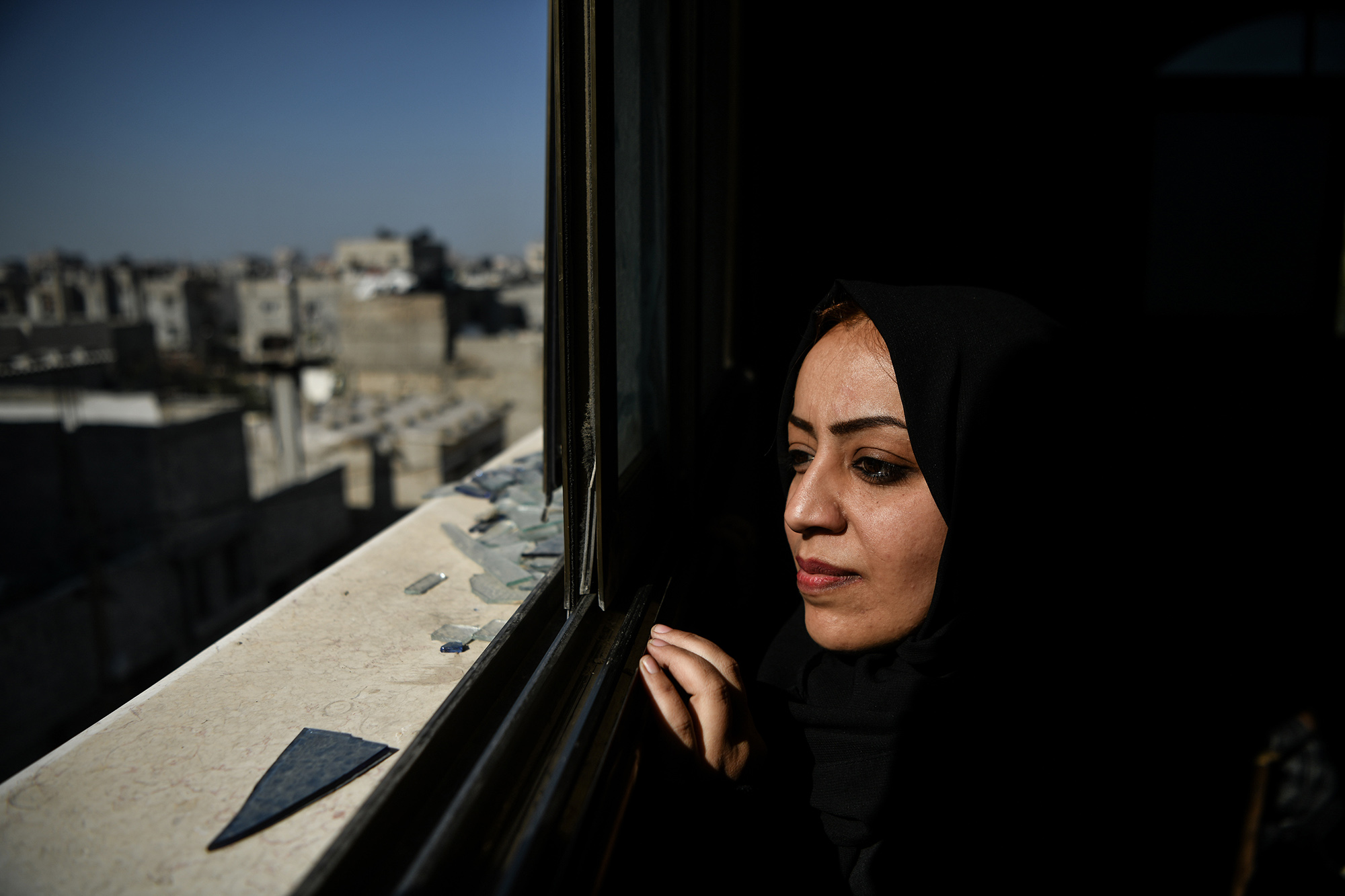 Un entrepreneure gazaouie regarde à travers une fenêtre brisée dans la ville de Rafah.