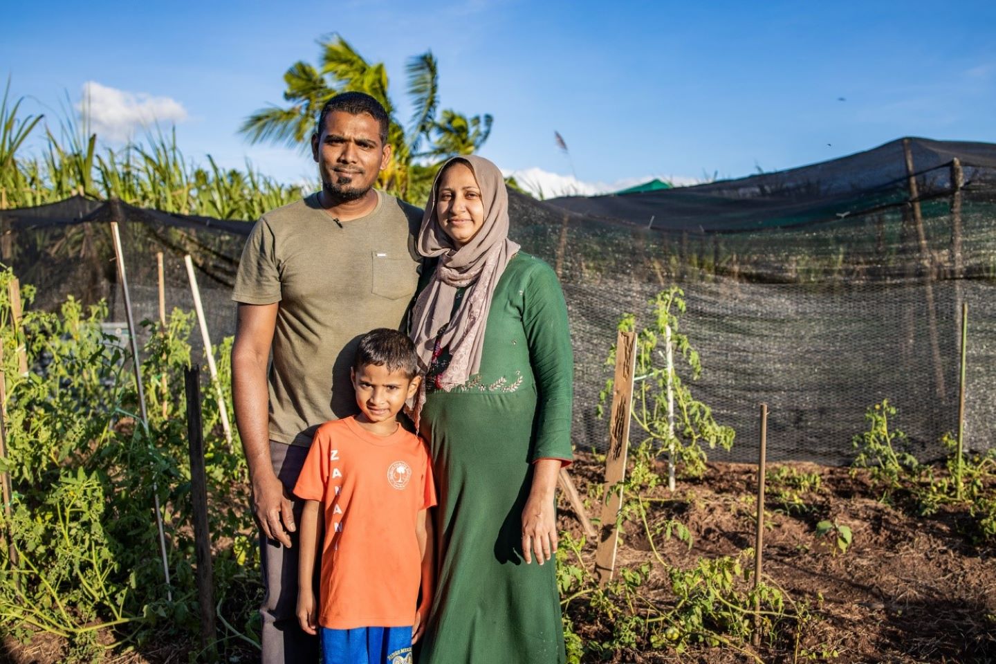 Une couple d'agriculteurs posent avec leur enfant dans un champ