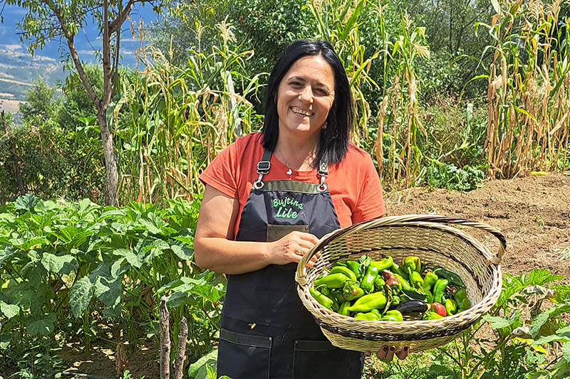 Une femme souriante tenant un panier de poivrons