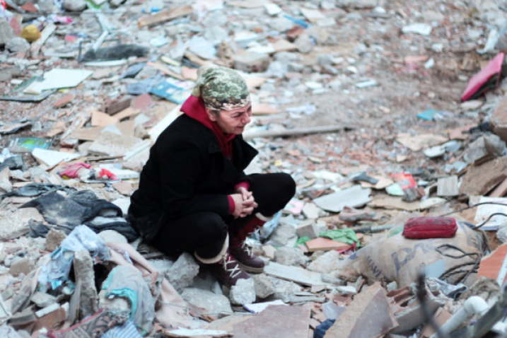 Photo d'une femme pleurant assise sur les décombres d'une habitation, servant de lien vers le site d'ONU Femmes