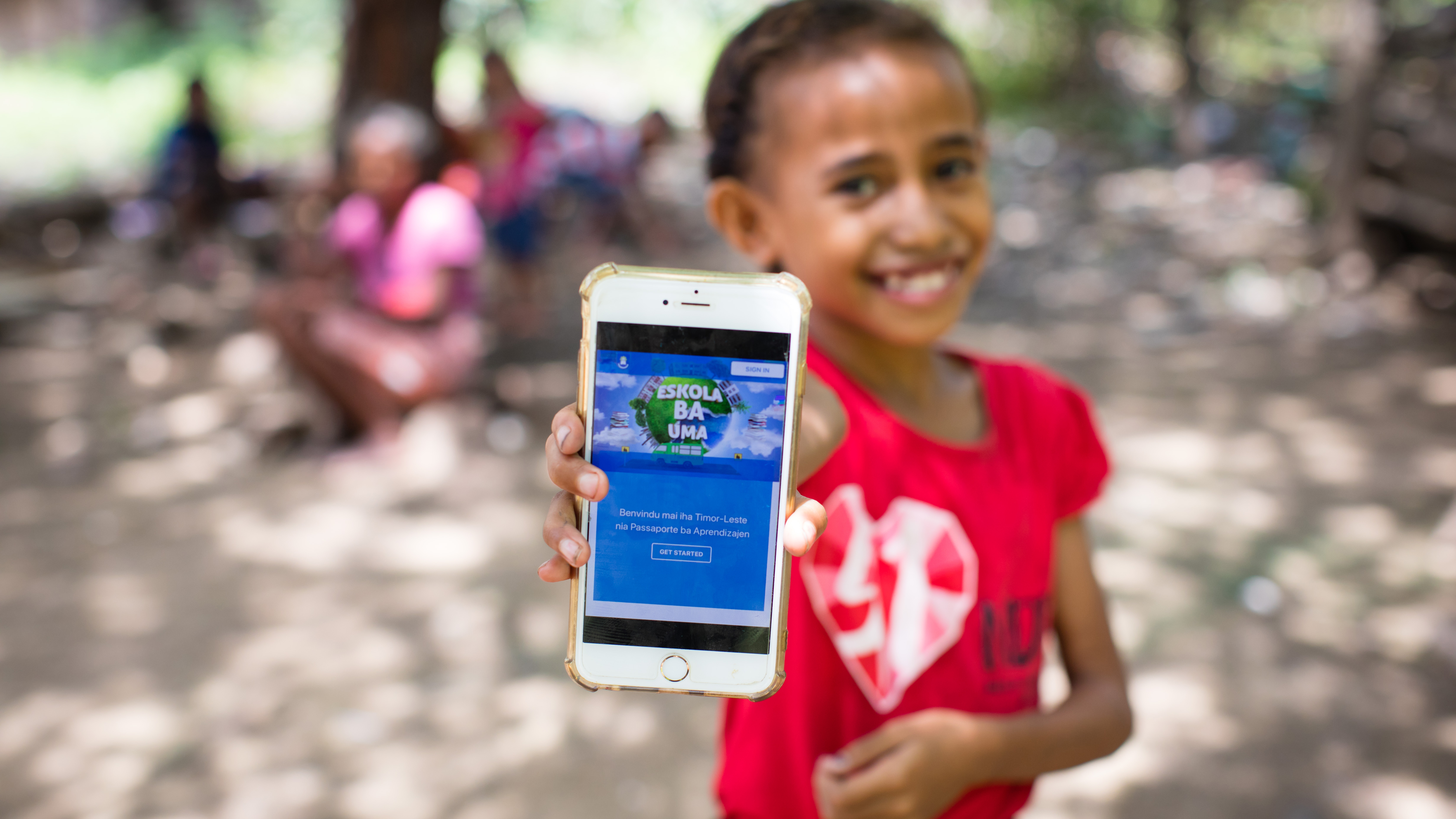 Une jeune fille tend son smartphone à la caméra. 