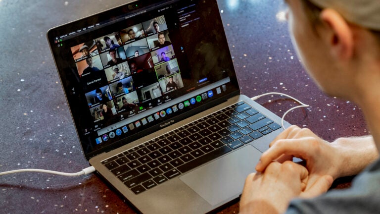 A student looking at a computer while attending a Zoom meeting.