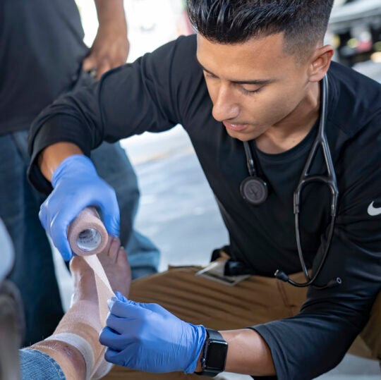 A USC Street Medicine team member wraps the leg of an unhoused person