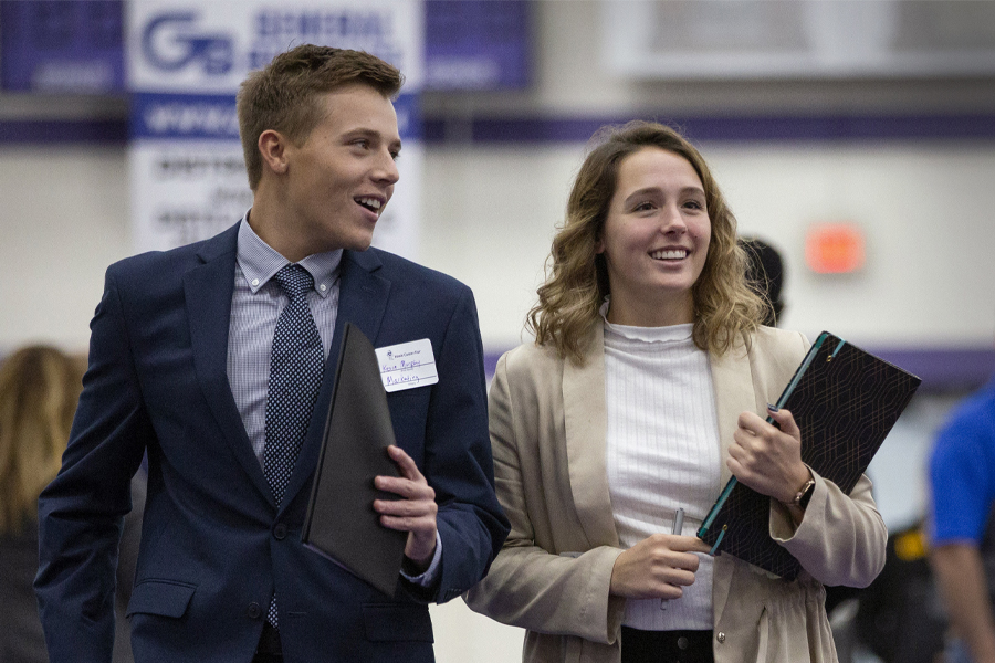 Two students wear professional attire as they walk together.