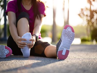 Young woman massaging her painful foot while exercising. Running Sport and exercise injury concept.