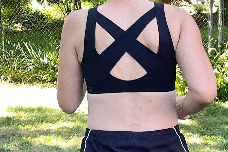 Closeup of a person's back in the lululemon Enlite Front Zip Bra High Support A-DDD Cups running outside