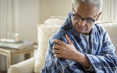 Senior African American man rubbing his shoulder