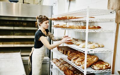 baker placing bread fresh from oven on cooling rack