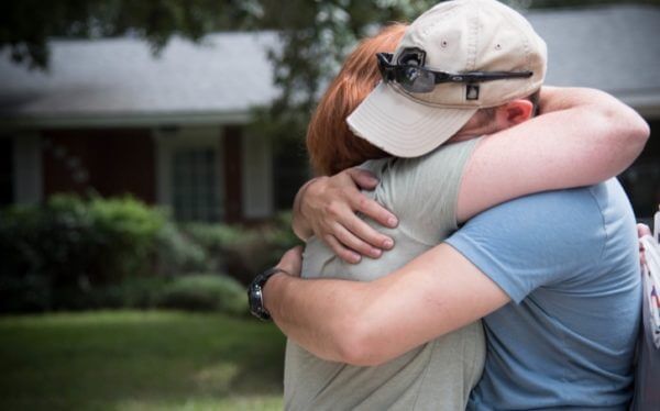 Man and woman hug in front of home