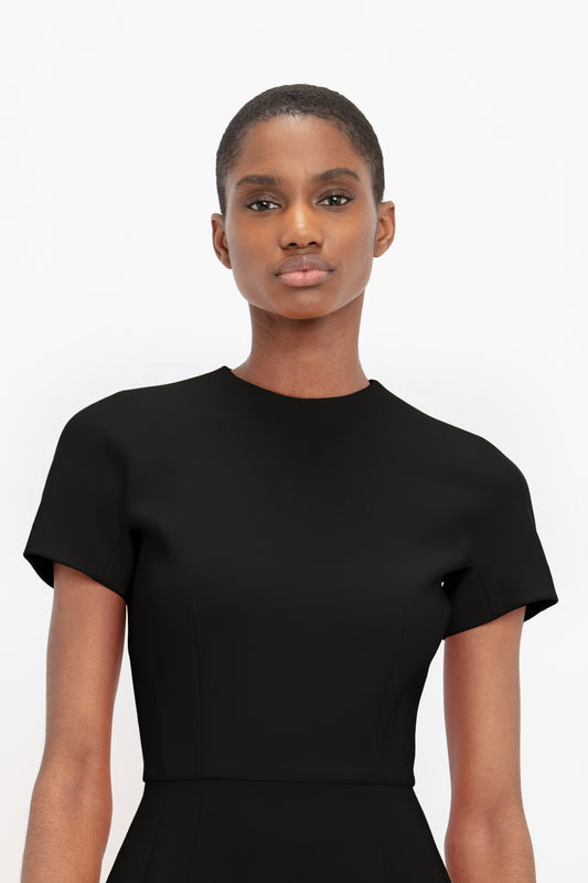 A person is shown in a studio setting wearing a Victoria Beckham Fitted T-Shirt Dress In Black.