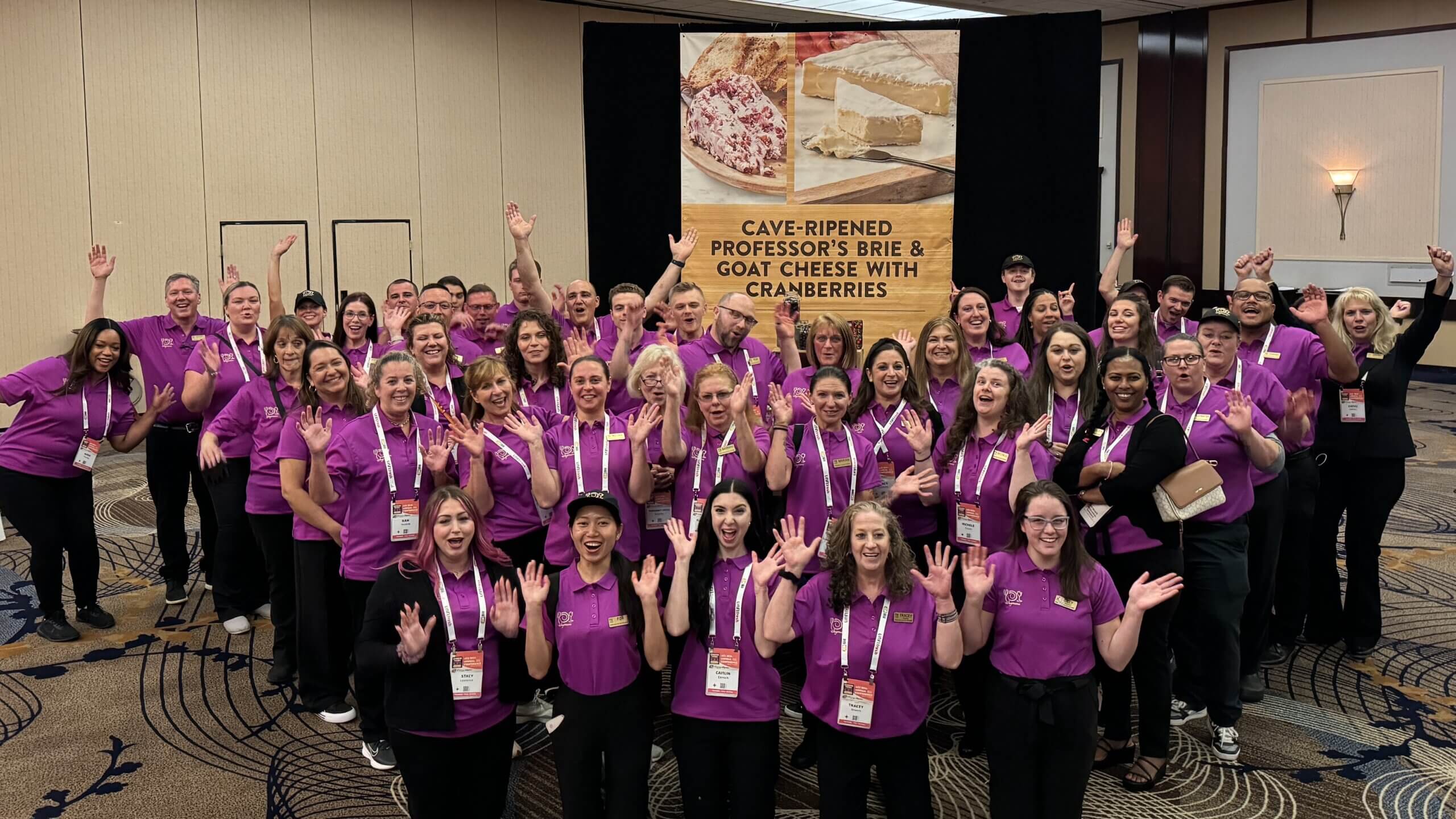 40 Wegmans employees in purple polos cheering for cheese!