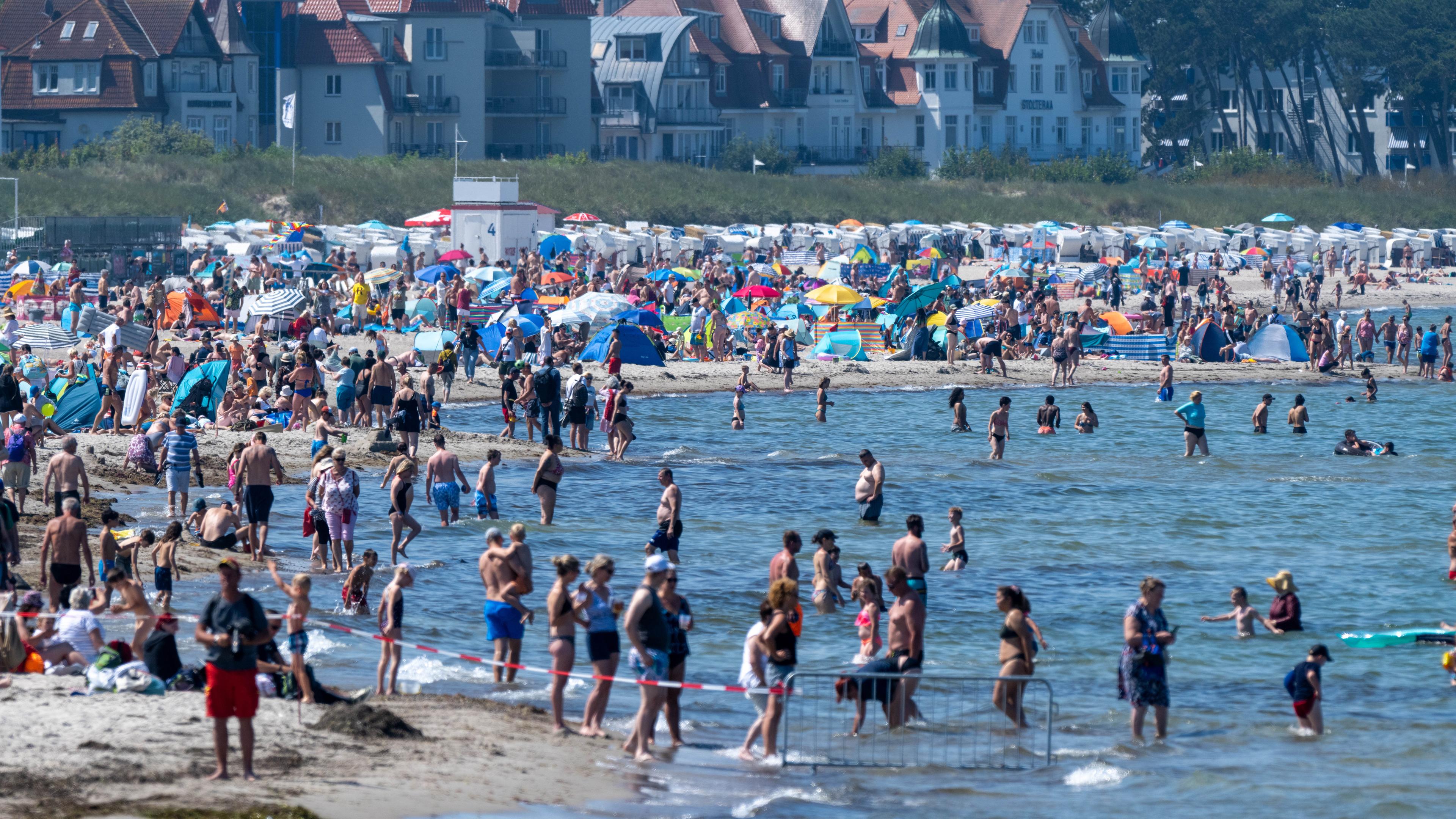 Touristen spazieren und baden am Strand der Ostsee.