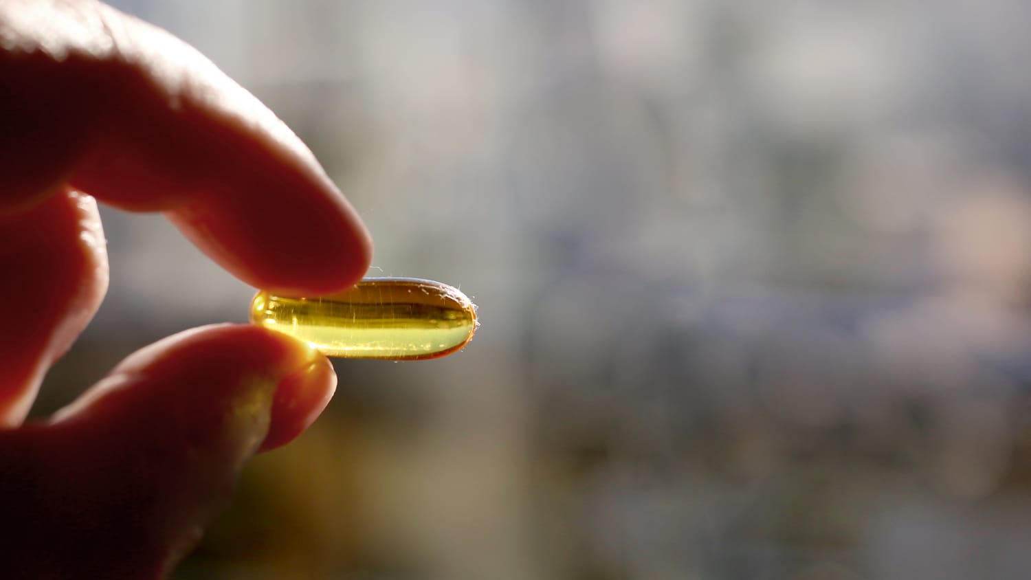 person holding vitamin d capsule